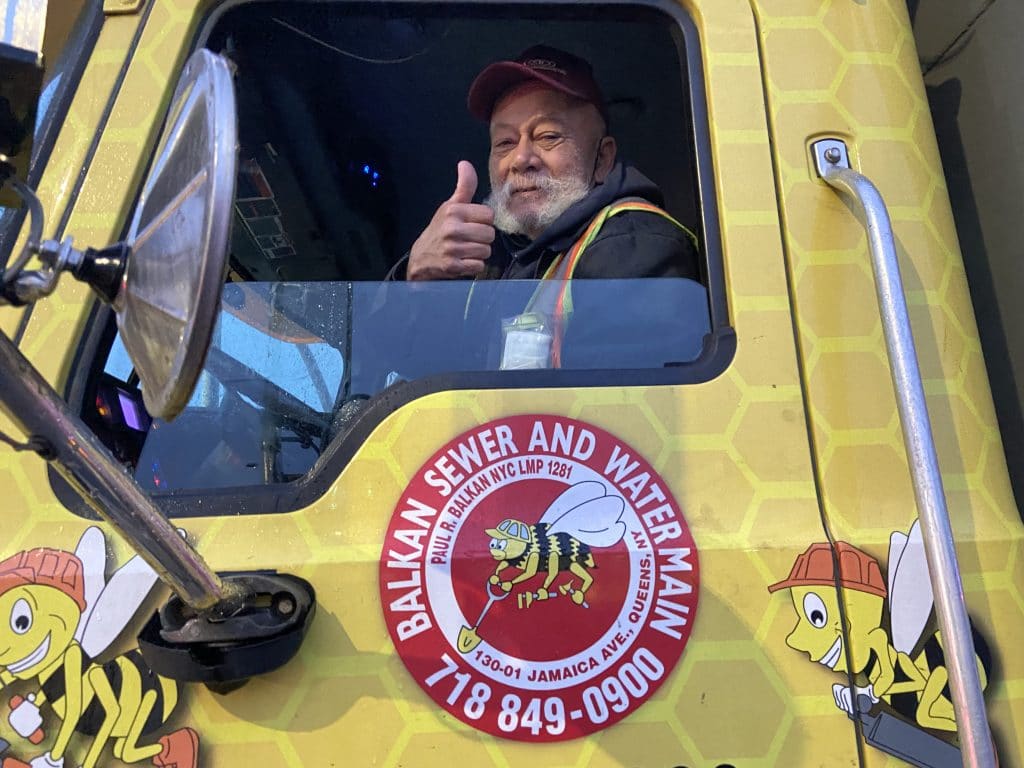 A man behind the wheel of a truck and makes the thumbs-up gesture.
