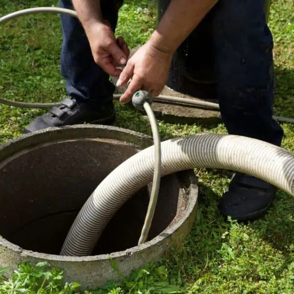 Most Common Causes of Sewer Backup Are For These Reasons 4 a man holding a hose in a concrete container