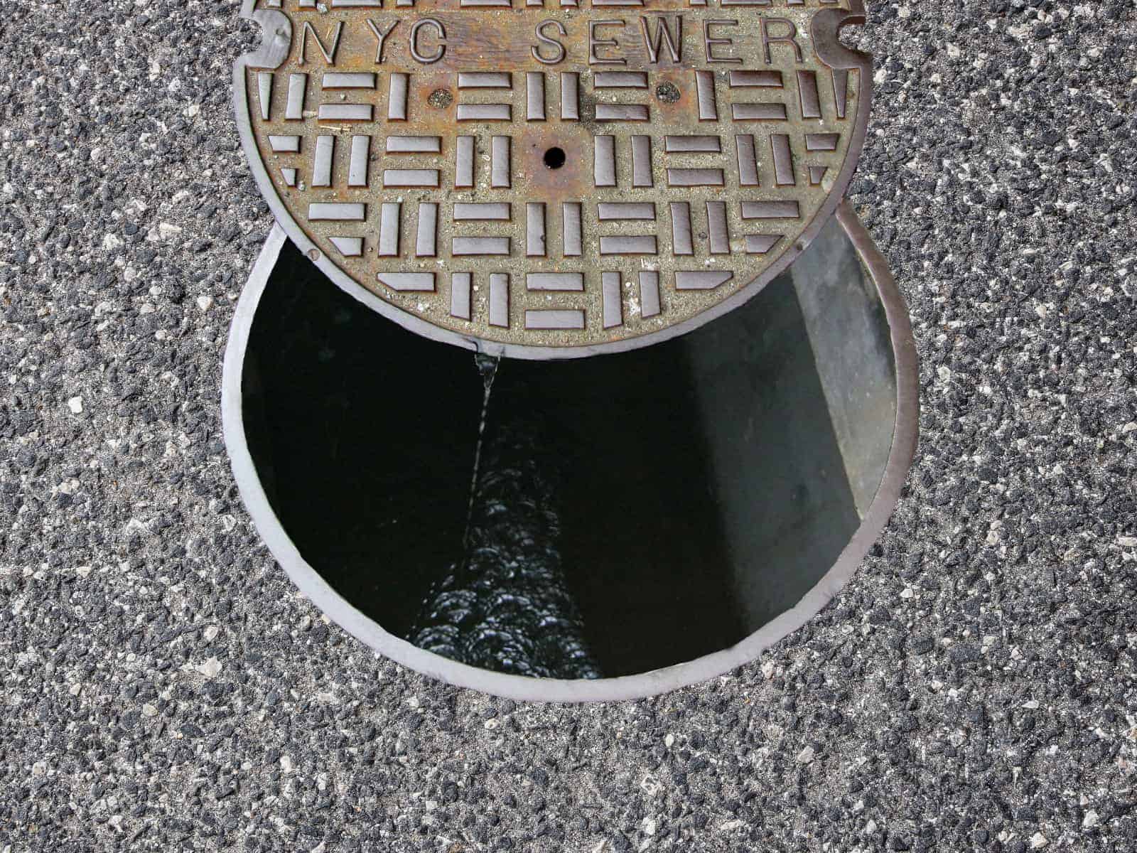 An open manhole cover revealing a hole in the pavement