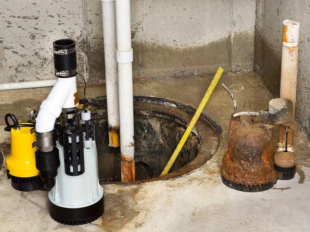 An old and rotted sump pump being repalced with a new sump pump.