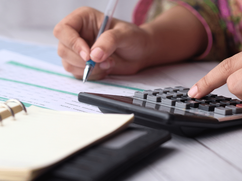 Hands of a girl doing mathematical accounts with a calculator and a pen